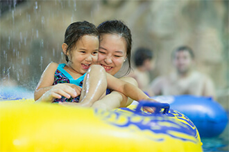 A mom and daughter float on a two-person tube