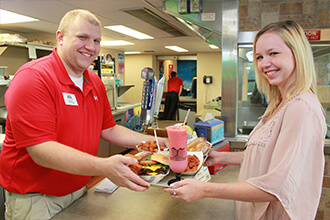 Man serves woman pizza and smoothie