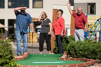 Group of four adults plays outdoor mini golf 